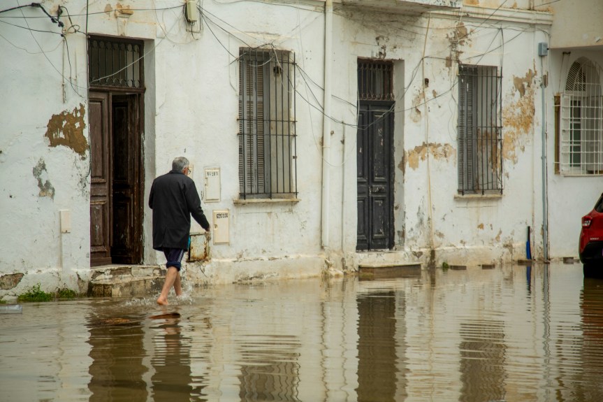 Man walks through flooded street in front of old buildings